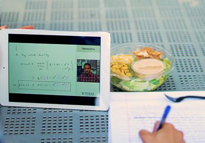 taking notes during online lecture displayed on tablet