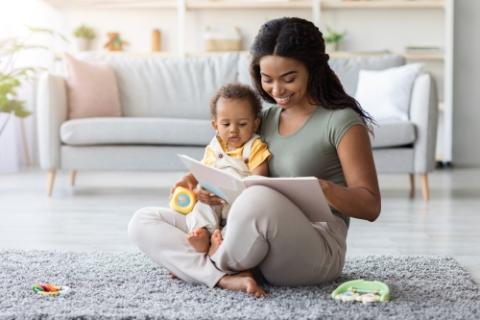 mother sitting on floor reading to infant