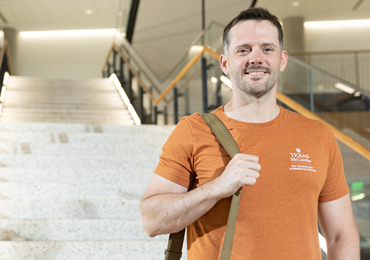 ut student standing in front of stairs with backpack