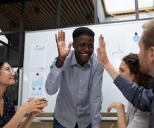 diverse professional team high-fiving during a meeting