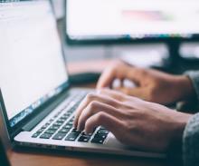 hands typing on a laptop keyboard