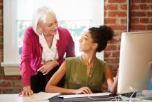 professional woman mentoring younger colleague at computer