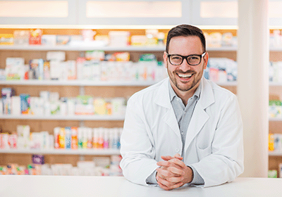 pharmacist leaning against counter smiling