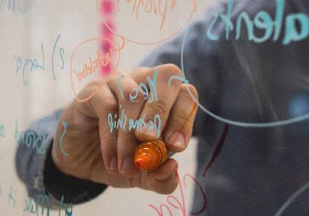 person writing on transparent marker board