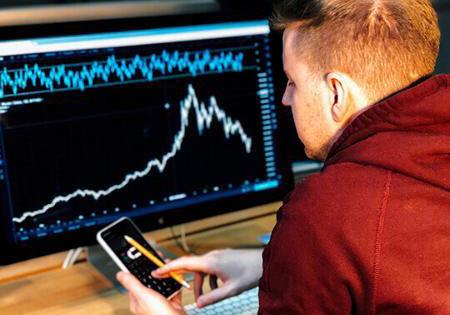Person comparing graphs on a computer and a smartphone
