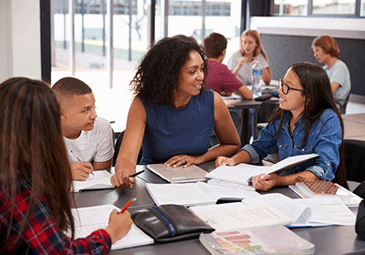 teacher engaging young student at desk