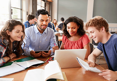 teacher and students gathered around laptop