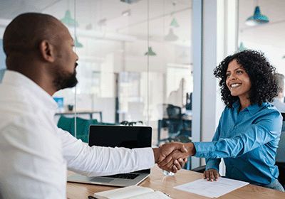 two professionals shaking hands at a desk