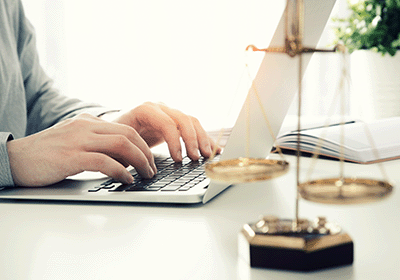 scales of justice in front of person working on laptop