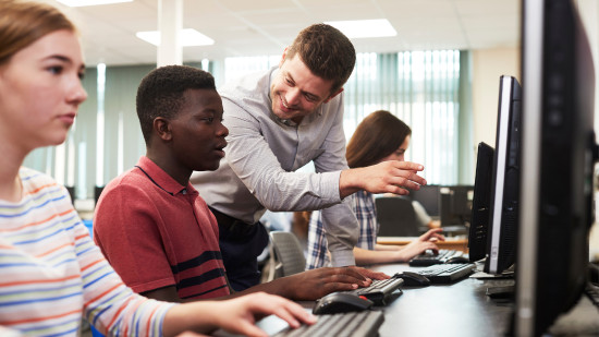 teacher instructing student on desktop computer
