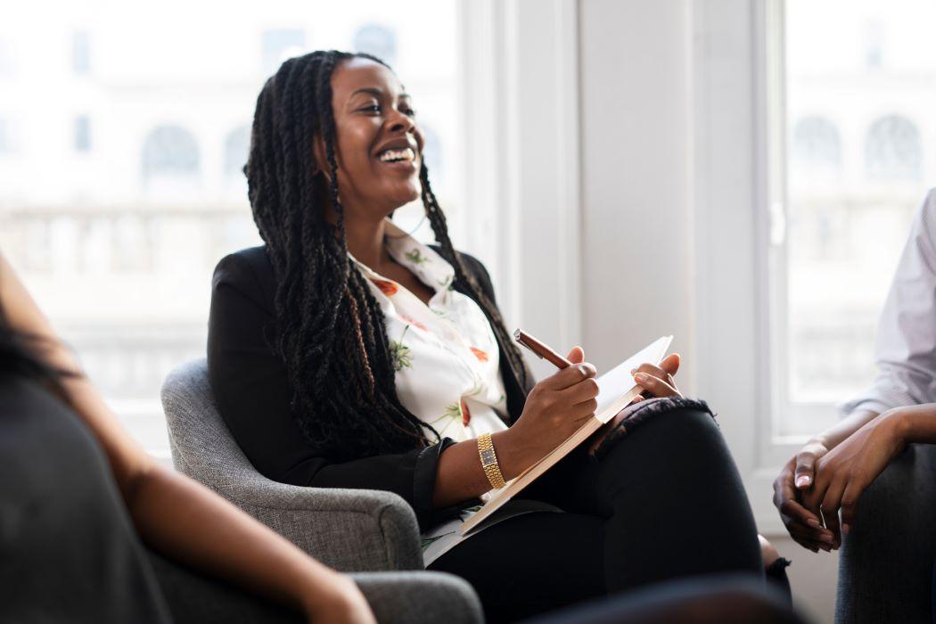 woman smiling and taking notes in a meeting