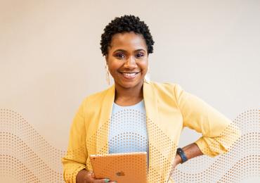 Woman of color smiling with tablet in hand 