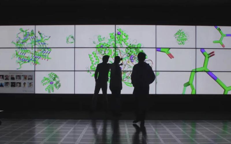 three silhouettes against illuminated panels displaying molecules