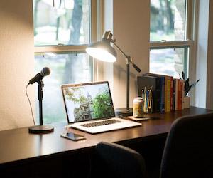 laptop at empty desk with microphone and lamp